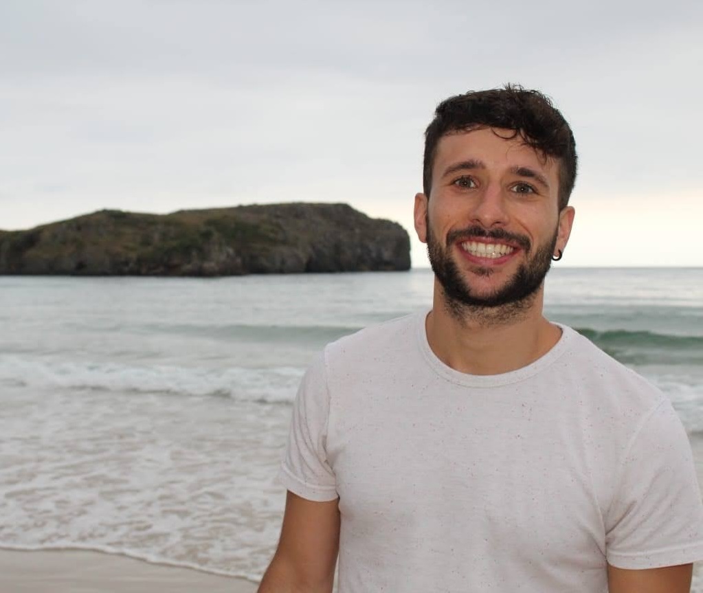Iñaki Arroyo Nebreda smiling on a beach with mountains and ocean in the background